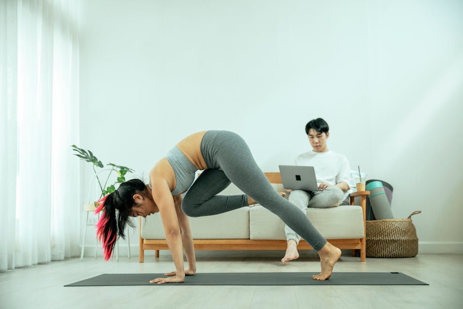 Man working from home on a laptop, pausing to take a mindful stretch on a yoga mat.